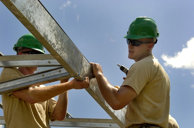 construction workey wearing yellow polo shirt and green safety helmet